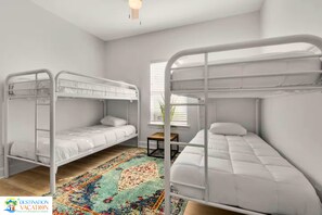 Quarto com beliches, uma mesinha e um tapete colorido.