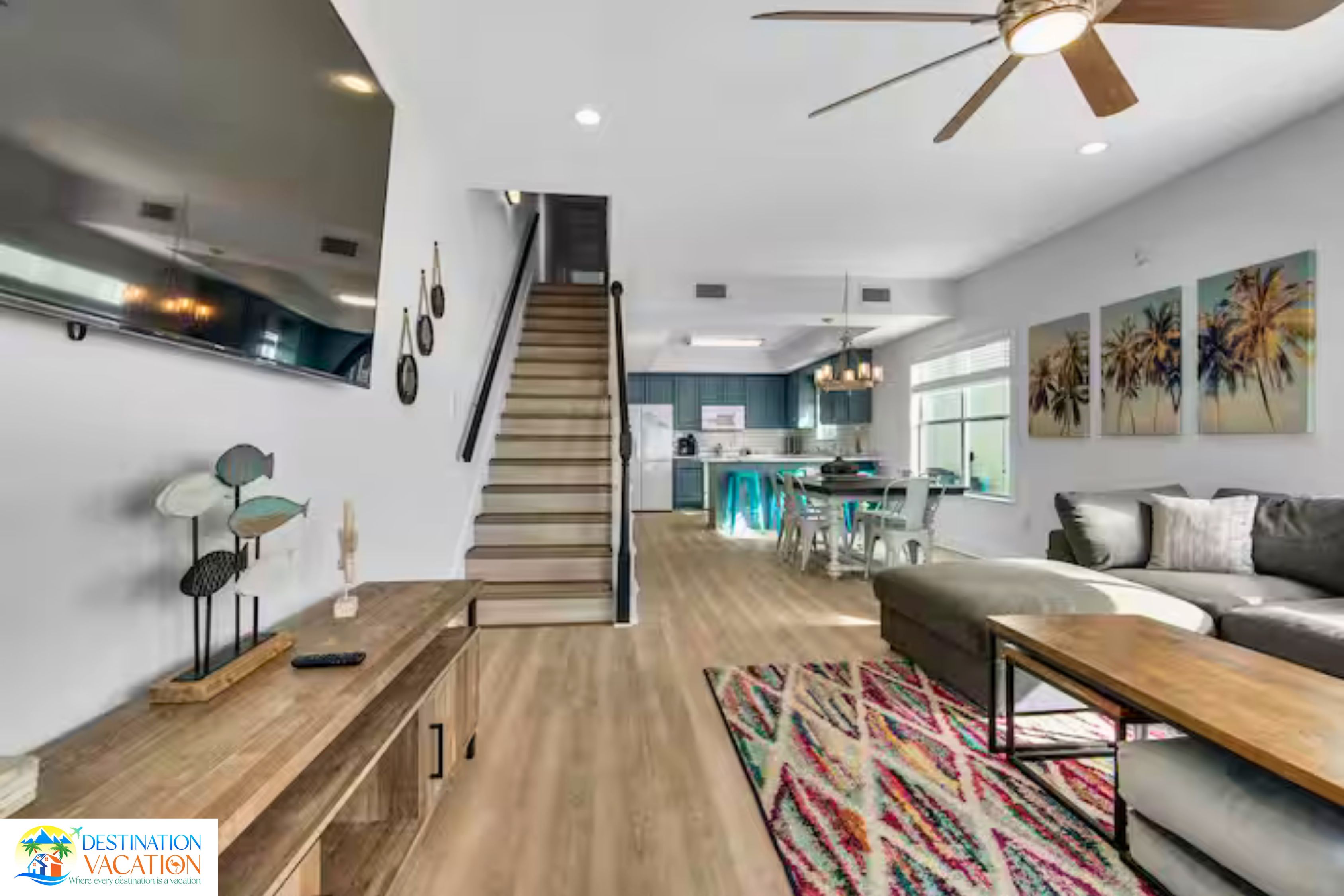 Un amplio salón con escalera, una mesa de comedor y una cocina al fondo.
