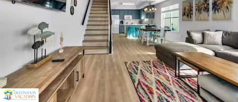 Un grand espace de vie comprenant un escalier, une table à manger et une cuisine en arrière-plan.