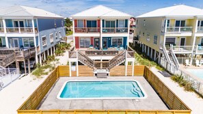 A beachfront property with a swimming pool, wooden deck, and multiple-story buildings with balconies.