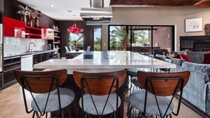 A modern kitchen with a central island, dining chairs, a sofa, and a fireplace. - Desert Hideaway+Shuffleboard Court+Golf+Billiards (Scottsdale)
