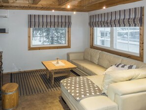 Ein gemütliches Zimmer mit einer Couch, einem kleinen Tisch und einem Fenster mit Blick auf Bäume.