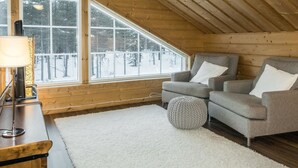 A cozy room with a sloped ceiling, wooden walls, and a large window offering a view of a snowy landscape. - Rapsakka a by Interhome (Kittilä)