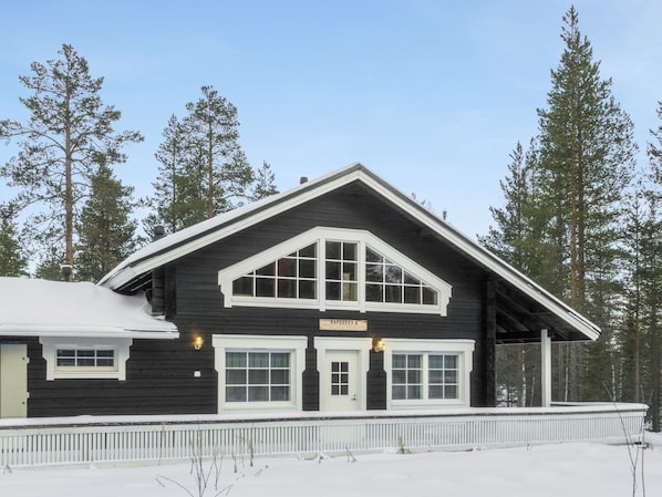 A two-story lodge with a dark exterior and white trim, featuring a prominent entrance and large windows.