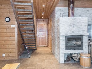 Ein Holzinnenraum mit Kamin aus Stein, einer Holztreppe und einer Metallleiter.