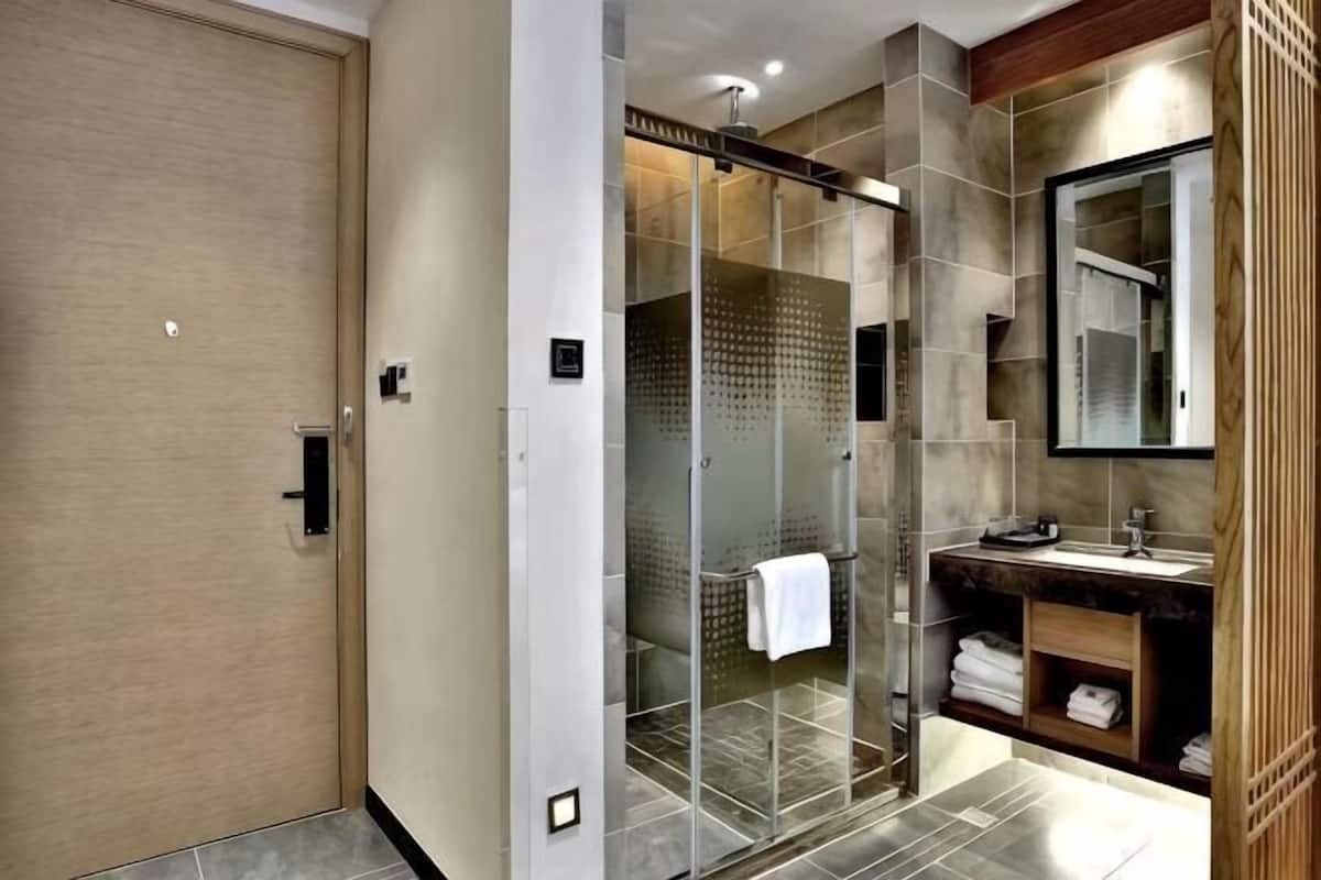 A modern bathroom with a glass shower enclosure, a wooden vanity, and a large mirror.