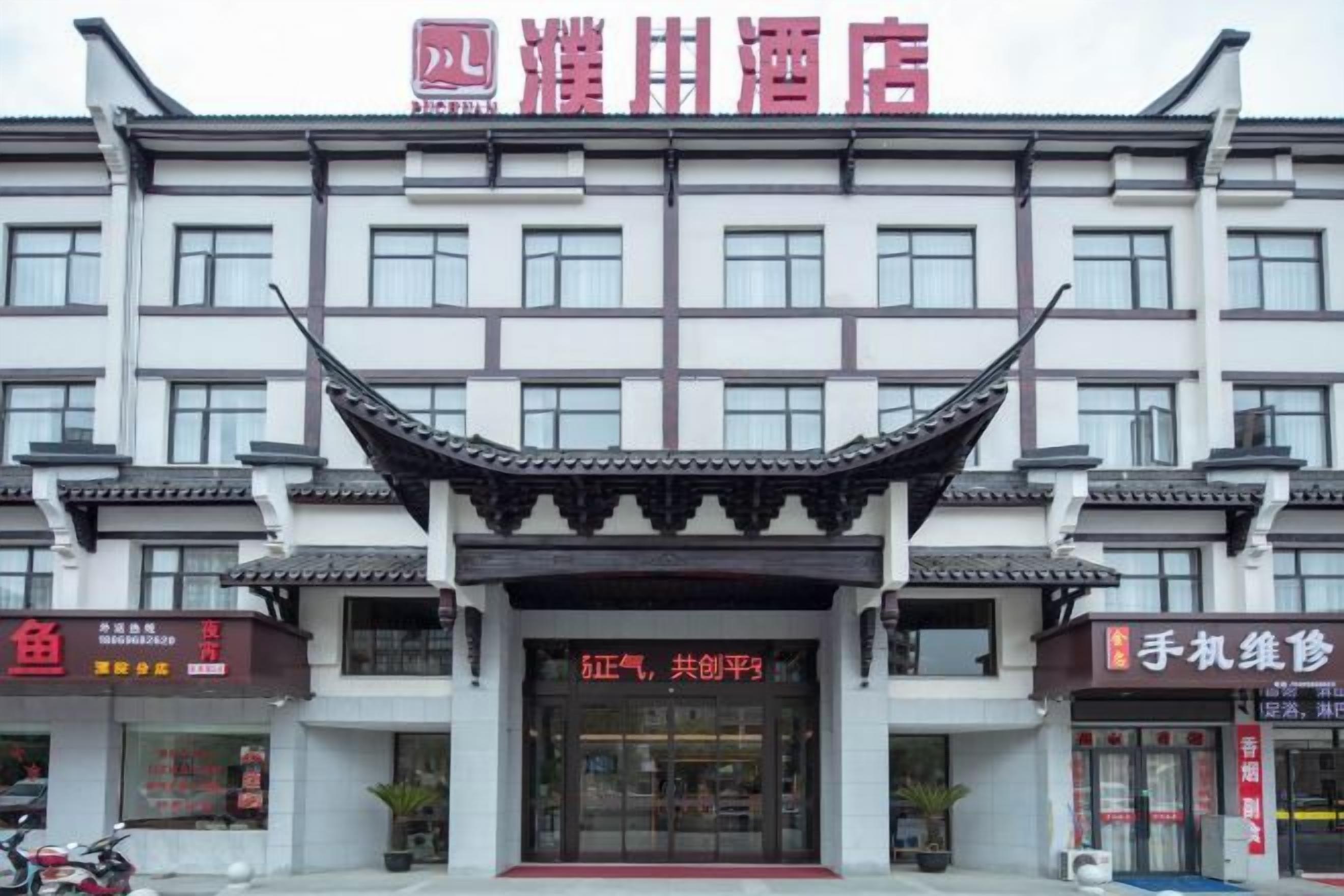 A hotel with a traditional Chinese architectural style, featuring a prominent curved roof and multiple windows.