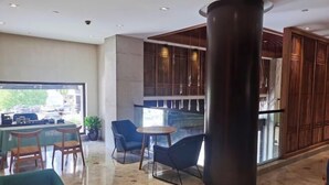 A modern interior with a large pillar, seating area, and a view through a glass wall. - Puchuan Hotel (Tongxiang)