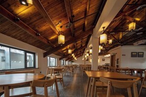 Un comedor amplio con techos de madera altos y varias mesas y sillas.