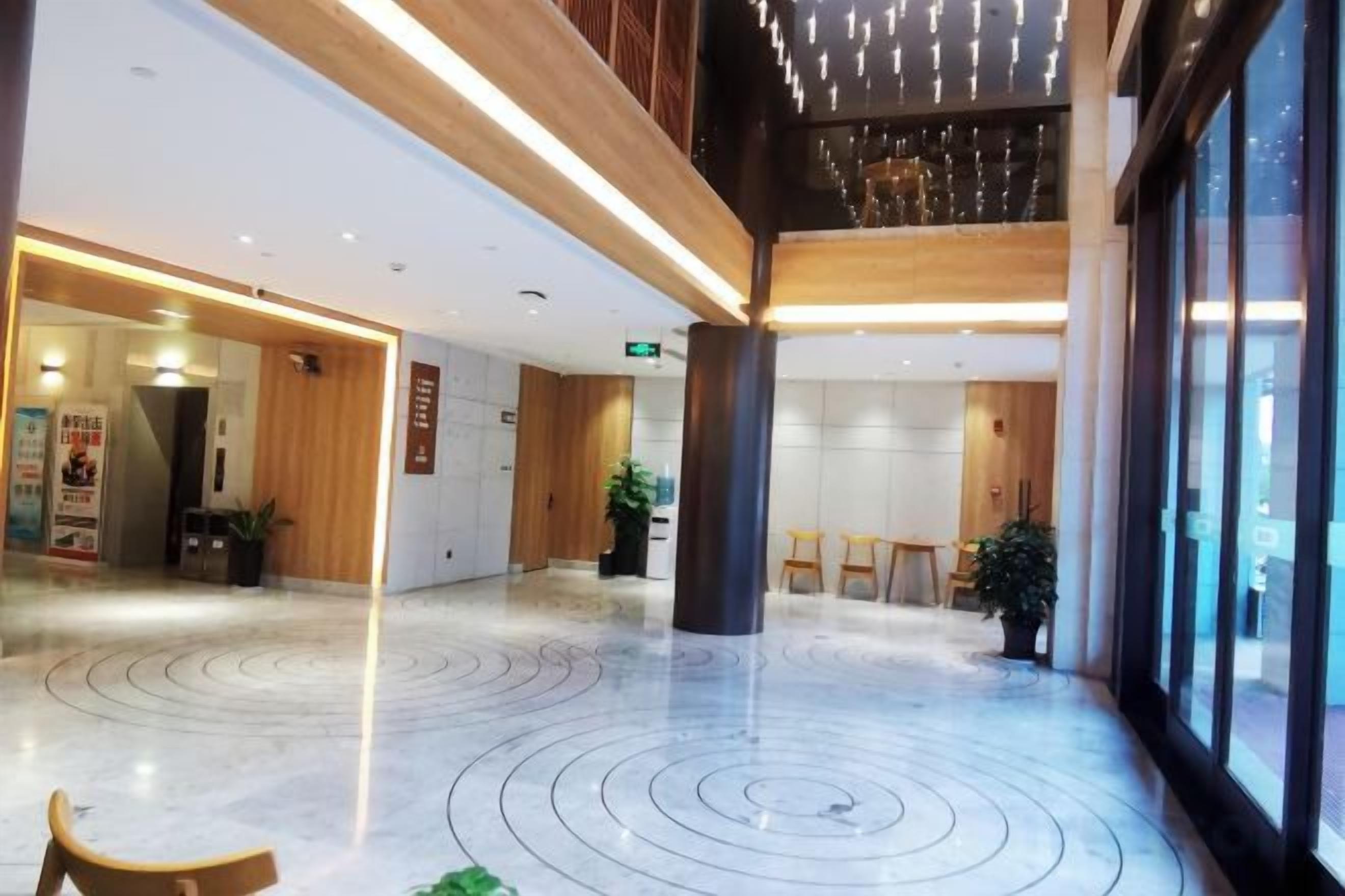 A spacious lobby with a marble floor, wooden accents, and large windows.