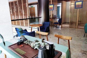 Un comedor con una mesa dispuesta para dos personas, una cafetera y una bandeja con teteras y tazas.