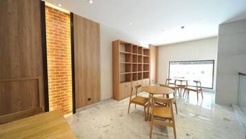 A modern room with a wooden table and chairs, a brick accent wall, and built-in shelving.