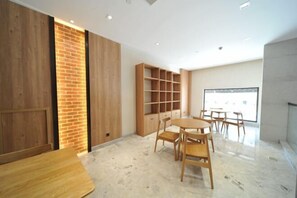 A modern room with a wooden table and chairs, a brick accent wall, and built-in shelving. - Puchuan Hotel (Tongxiang)