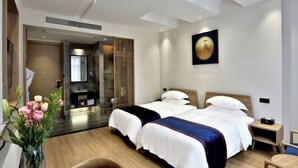 A hotel room with two beds, a wooden floor, a bathroom with a mirror, and a painting on the wall. - Puchuan Hotel (Tongxiang)