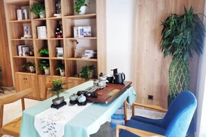 A room with a long table, a bookshelf, and a blue chair. - Puchuan Hotel (Tongxiang)