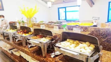 Un buffet garni de différents plats, avec une personne à l'arrière-plan.