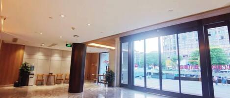 A spacious lobby with a polished floor, large windows, and a reception desk.