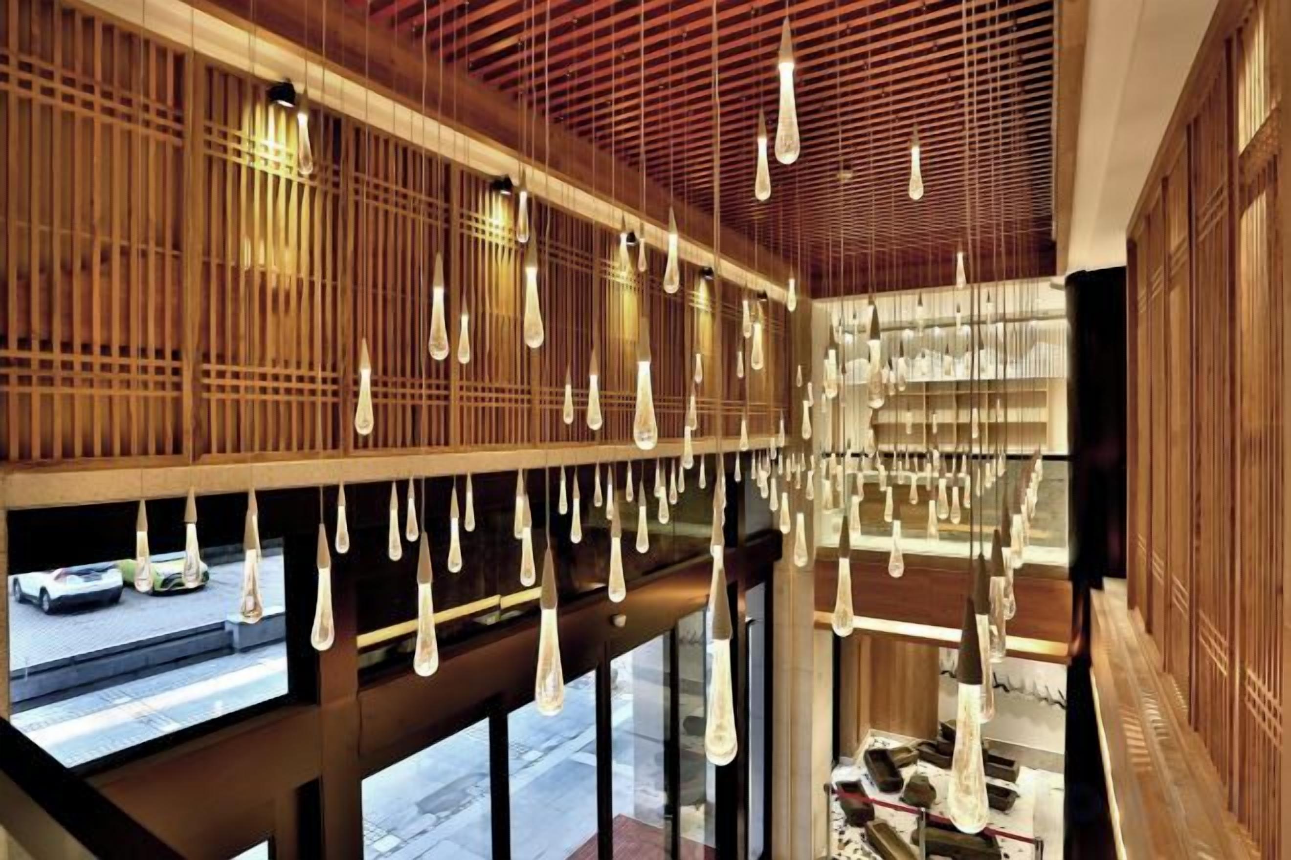 A modern interior with a wooden slatted ceiling and hanging light fixtures.