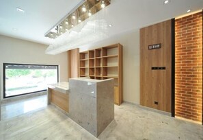 A reception area with a marble counter, wooden shelving, a brick accent wall, and a large window. - Puchuan Hotel (Tongxiang)