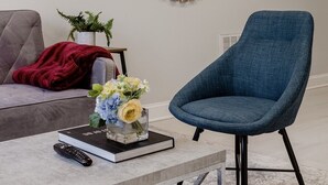 A modern living room with a grey sofa, a blue armchair, a round mirror, and a small table with a book and remote control. - Georgetown - 1-BR- Apt #1-450 SF (Near CAMPUS)  (Washington)