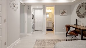 A modern bedroom with a bed, a desk, and a chair. There is a door leading to a bathroom and a hallway. - Georgetown - 1-BR- Apt #1-450 SF (Near CAMPUS)  (Washington)
