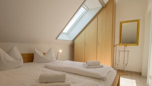 A bedroom with a skylight, wooden wardrobe, and a mirror. - Modern vacation apartment right on the beach with balcony - Residenz am Strand (Zingst)