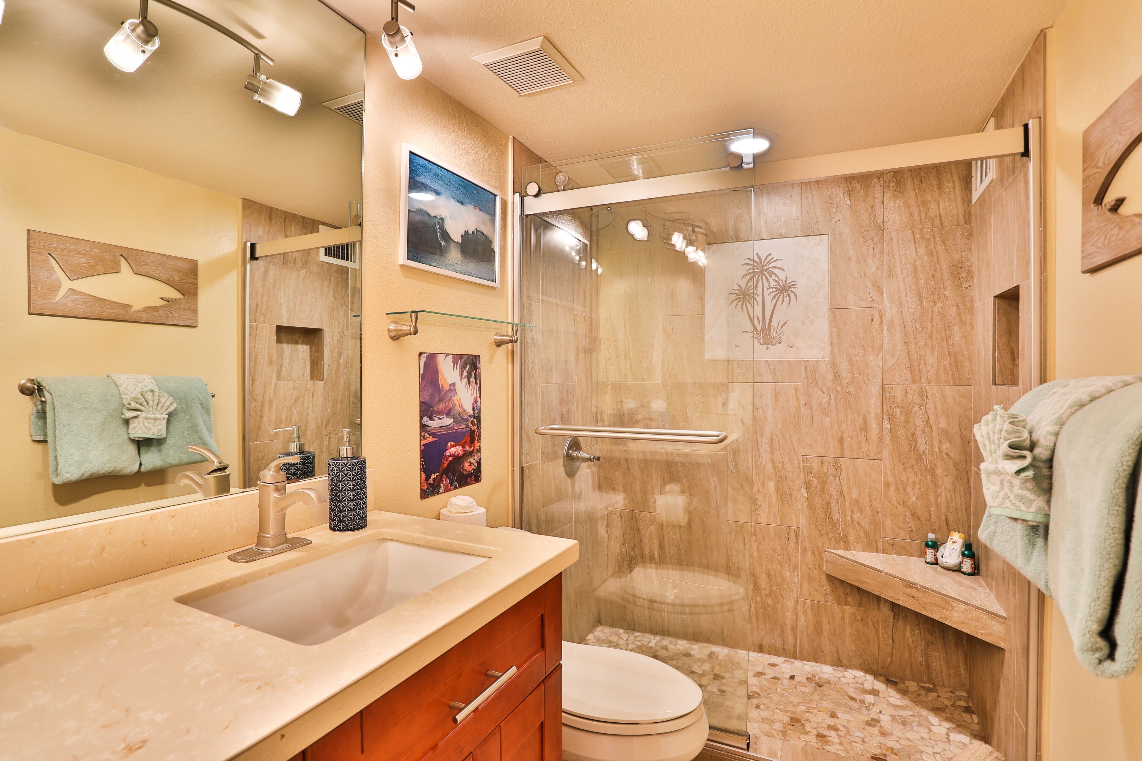 A bathroom with a large sink, a toilet, and a glass-enclosed shower.