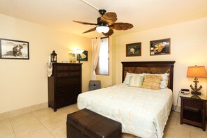 A bedroom with a bed, a nightstand, a dresser, a ceiling fan, and a window with curtains. - Kihei, Maui - Fully Renovated, A/C, Pool, Tennis, Beach  (Kihei)
