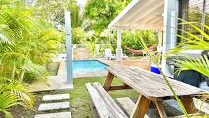 A backyard with a swimming pool, a wooden picnic table, and a hammock. - Serenity By the Beach, Private pool & El Yunque rainforest. 2BR. - 2 FULL BA. (Luquillo)