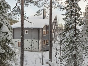 Um edifício moderno de vários andares, rodeado por árvores cobertas de neve.
