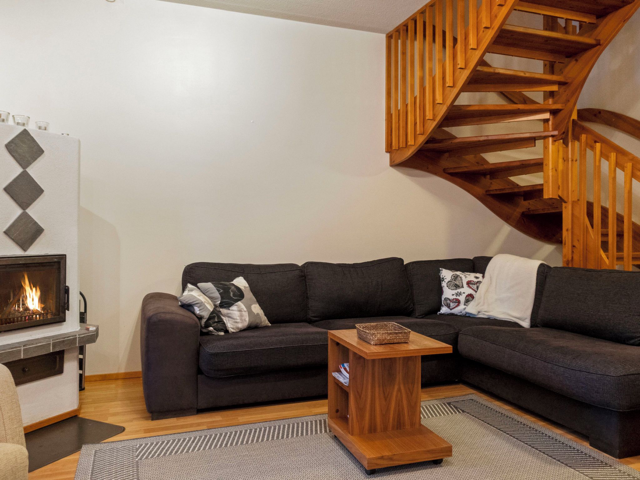 Una sala de estar con un sofá, una mesita de madera, una chimenea y una escalera de madera.