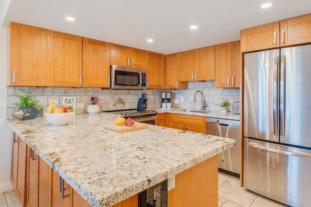 A modern kitchen with wooden cabinets, a granite countertop, stainless steel appliances, and a built-in oven.