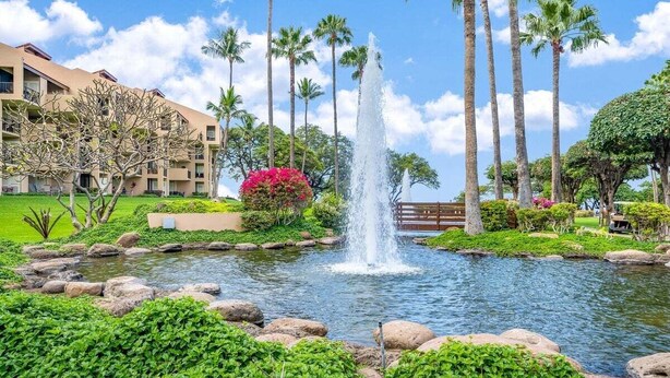 A landscaped garden with a central water feature, palm trees, and a building with balconies.