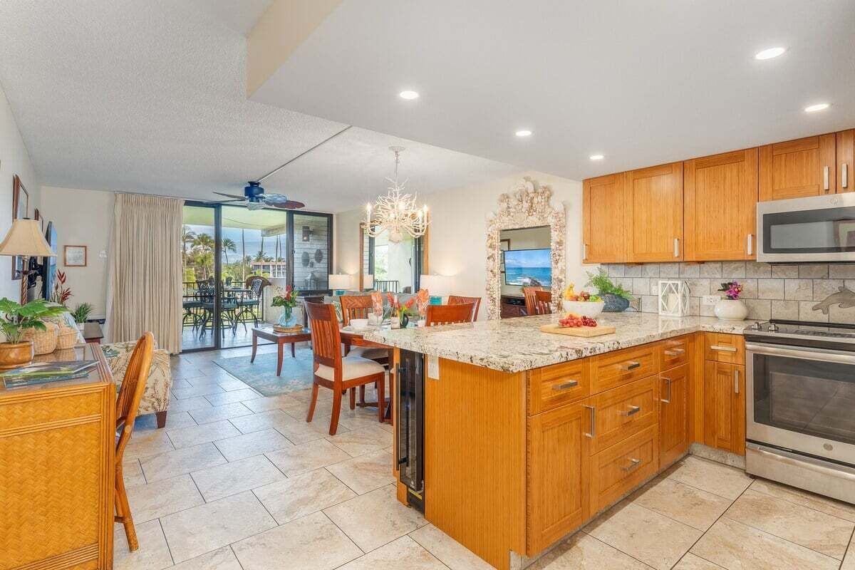 A spacious kitchen with wooden cabinets, a large island, and a view to the outdoors.