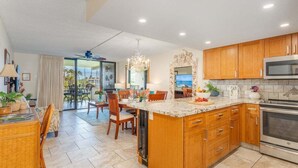 A spacious kitchen with wooden cabinets, a large island, and a view to the outdoors.