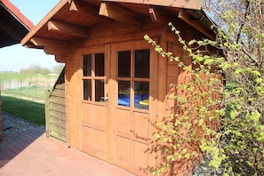 A wooden cabin with a sloped roof, a large window, and a door.