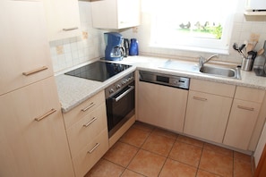 A compact kitchen with a stove, oven, dishwasher, and a coffee maker.