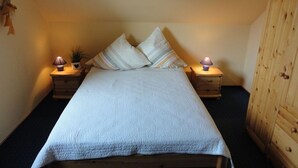 A bedroom with a bed, two bedside tables, a lamp, a wardrobe, and a small plant. - Friesenstern - Holiday home (100sqm) for 6 persons with garden in a quiet location of (Norden)