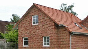 A two-story brick house with a red-tiled roof, two windows, and a visible gutter system. - Friesenstern - Holiday home (100sqm) for 6 persons with garden in a quiet location of (Norden)