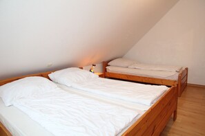 A small, single-room with two wooden bunk beds, a nightstand, and a lamp.