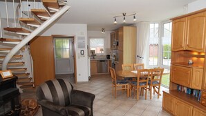 Un salon chaleureux avec une cheminée, un coin repas avec des meubles en bois et une cuisine équipée d’un réfrigérateur et d’une cuisinière.