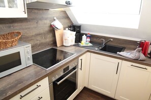 A modern kitchen with a built-in stove, oven, and sink. - Dornröschen - Ferienwohnung mit Direktem Wasserblick (Krummhörn)