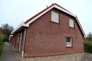 A red brick building with a gabled roof, a small window, and a door.