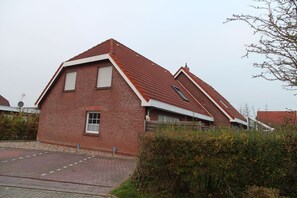 A red brick house with a steeply pitched roof, a small front window, and a visible garage door.