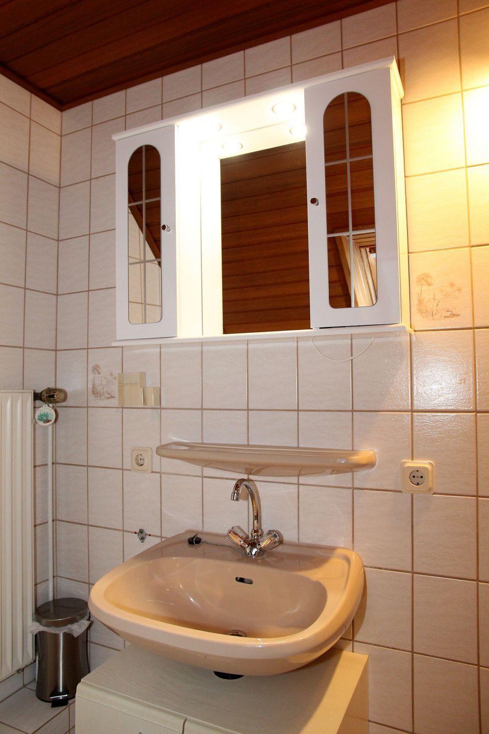 A bathroom with a white sink, a mirror above it, and a tiled wall.