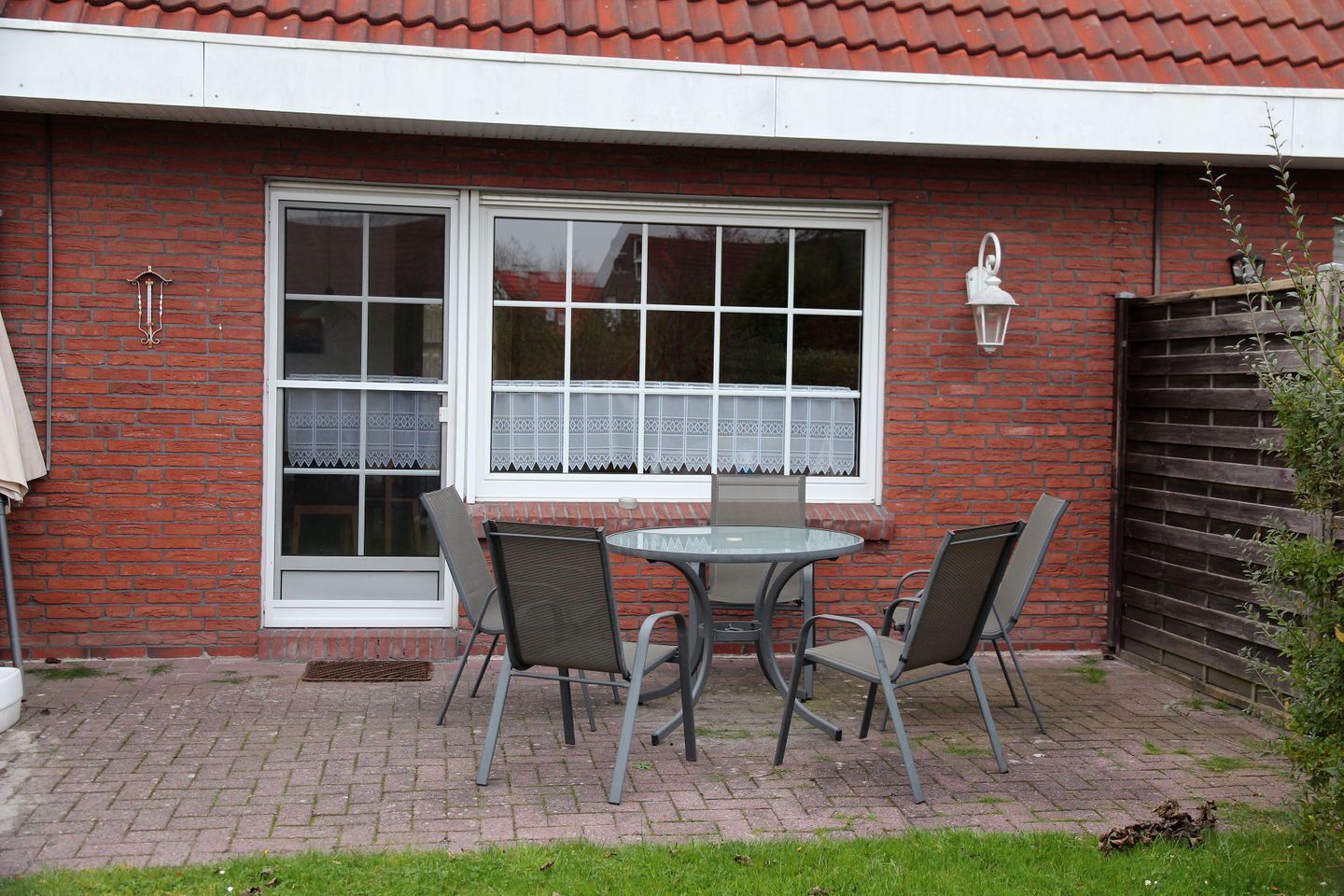 Ein Backsteinhaus mit Terrasse, auf der ein runder Tisch und vier Stühle stehen.