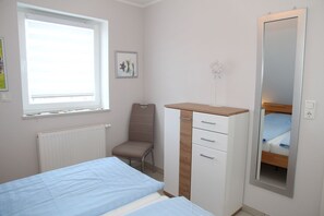 Un dormitorio con cama, cómoda, silla, ventana y espejo.