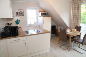 Una cocina compacta con un lavamanos, un microondas y un comedor con mesa y sillas.