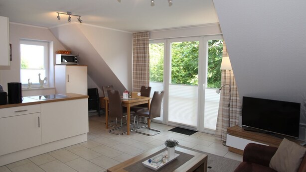 A compact living space with a kitchenette, dining area, and a TV. - Wattwunder - Schöne Ferienwohnung mit Inkludiertem Strandkorb am Strand (Norden)