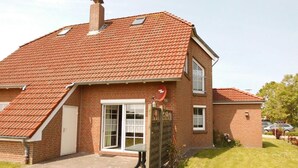 A two-story brick house with a red-tiled roof, a chimney, and a small attached garage. - Sandrose - Semi-detached house (85sqm) for 4 persons with garden in a direct (Norden)